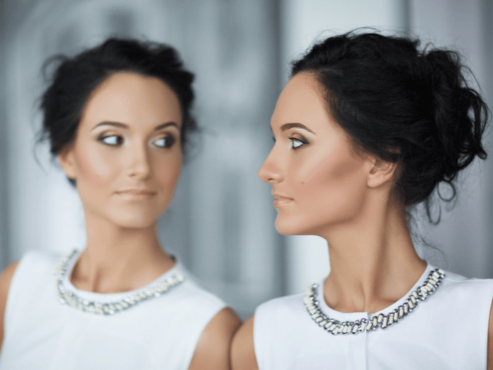woman in front of a mirror or with a doppelganger