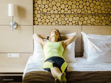 Photo of a woman laying in bed in workout clothes