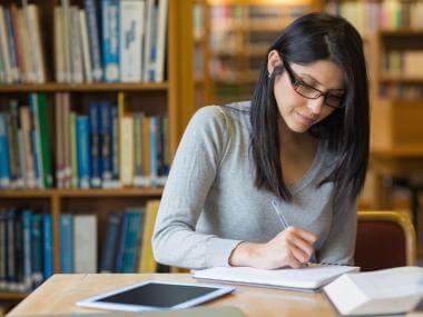 A picture of a woman writing in a library
