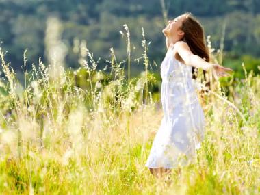 A girl twirling in a sunny field of flowers