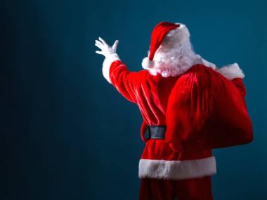 A photo of Santa Claus from behind in front of a solid blue background