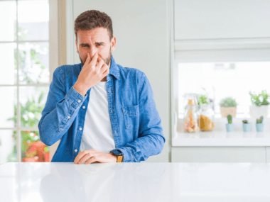 man smelling something bad in his home