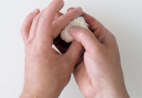 Gently place the thumb of your guide hand on the center of the rice, and the thumb and forefinger of the other hand on the ends of the rice
