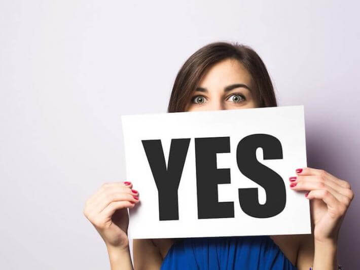 A woman holding a sign that says "yes."