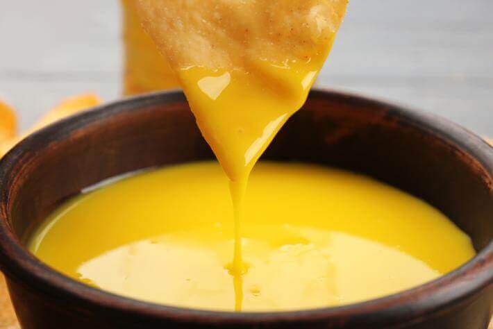 dipping a chip in cheese sauce