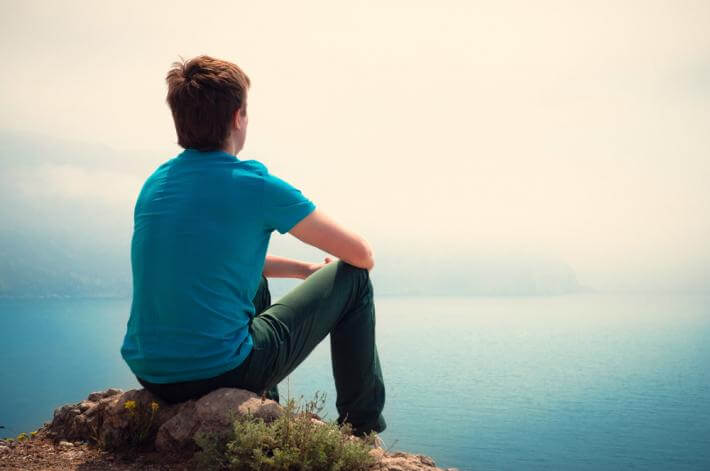 lonely guy sits on rock