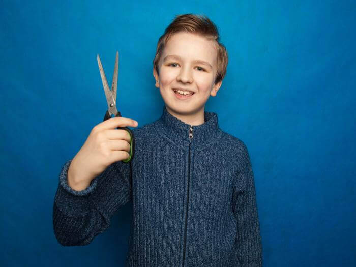 young boy holds scissors