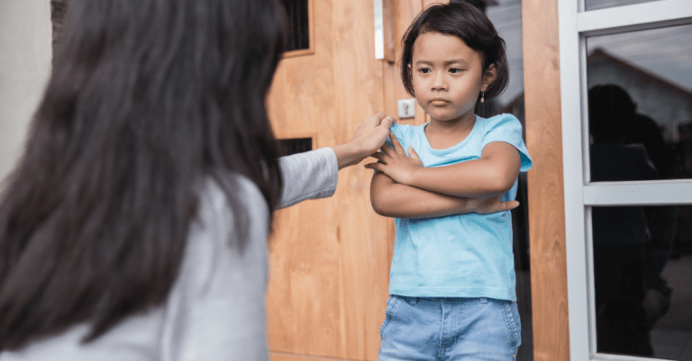 a little girl with her arms crossed looking stubborn and defiant with her mother