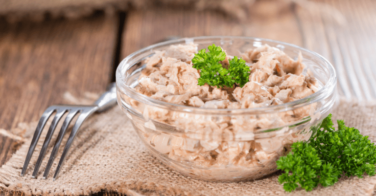 tuna topped with broccoli in a glass bowl on a wooden table