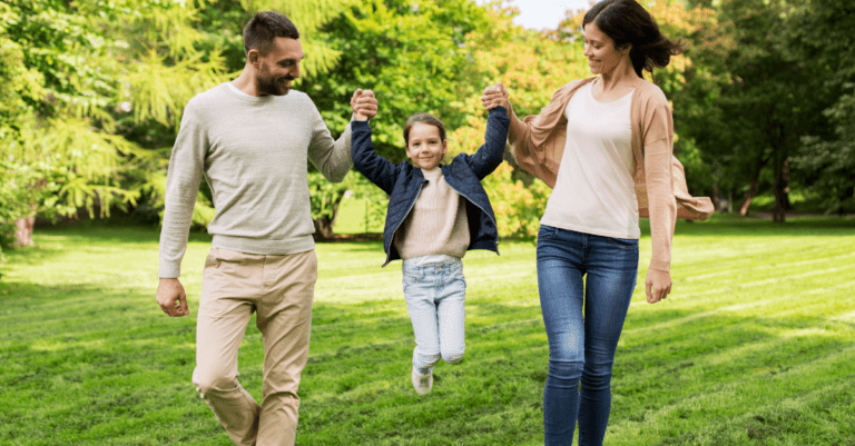 family walking together and playfully lifting child up