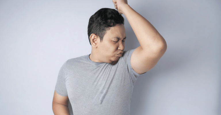 a man sniffing his armpit and making a face