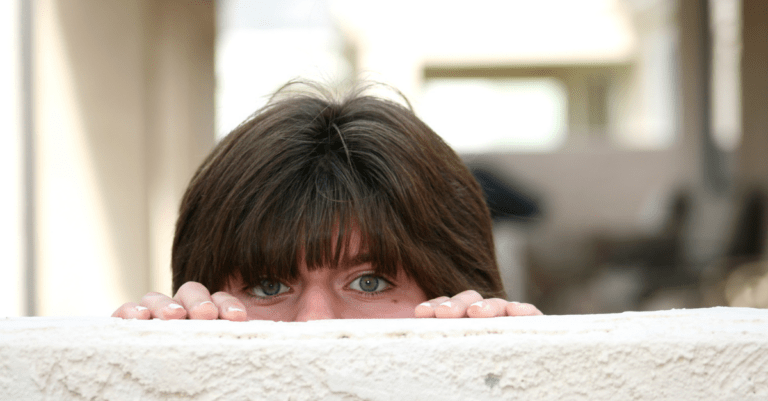 a person being nosy and peaking over a wall