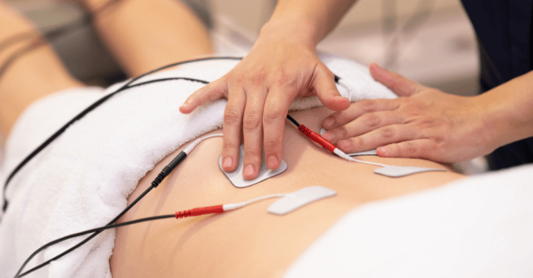 a doctor using electrical muscle stimulation on the lower back of their patient
