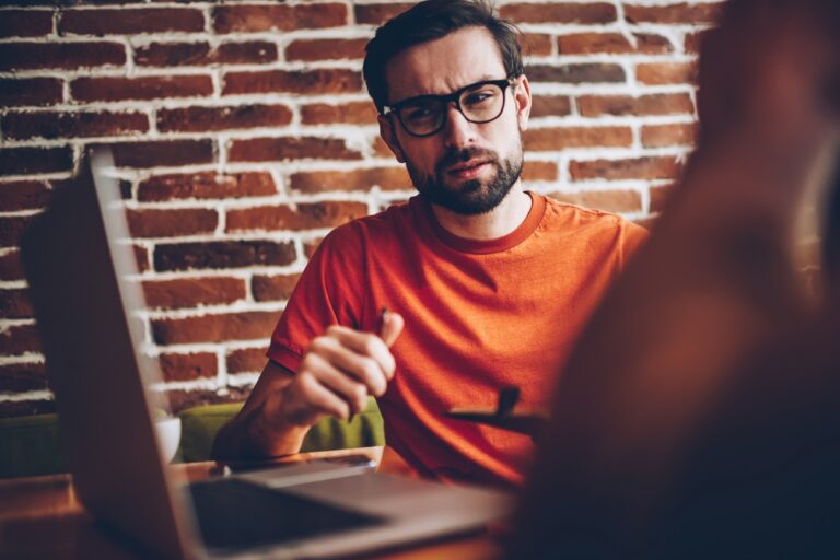 Man in glasses at a computer with a skeptical look