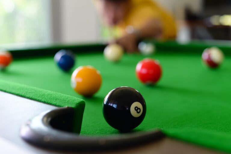 Billiard palls on a pool table with the black 8 ball next to pocket.