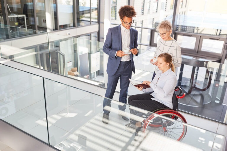 Two people standing and one in a wheelchair at work