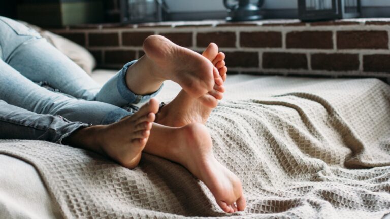 Feet interlaced on a bed