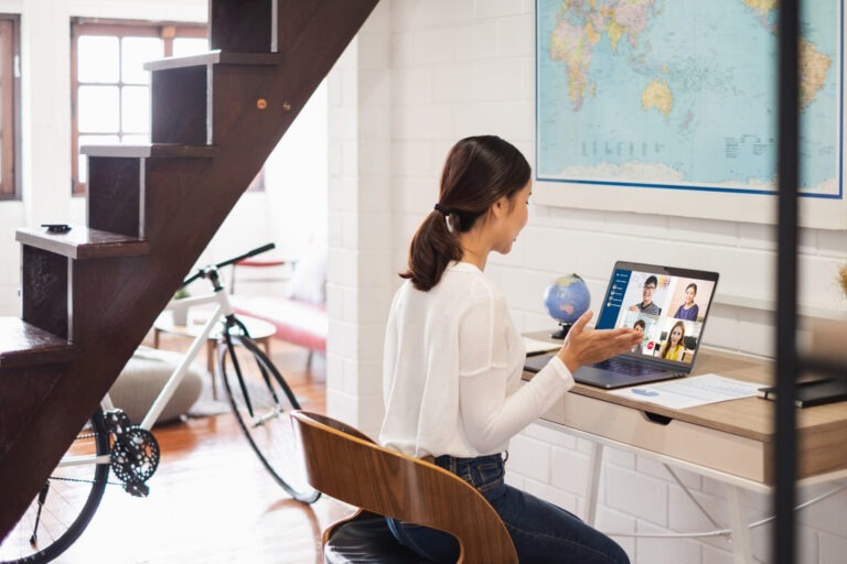 Woman at desk in her home, with bike and stairs