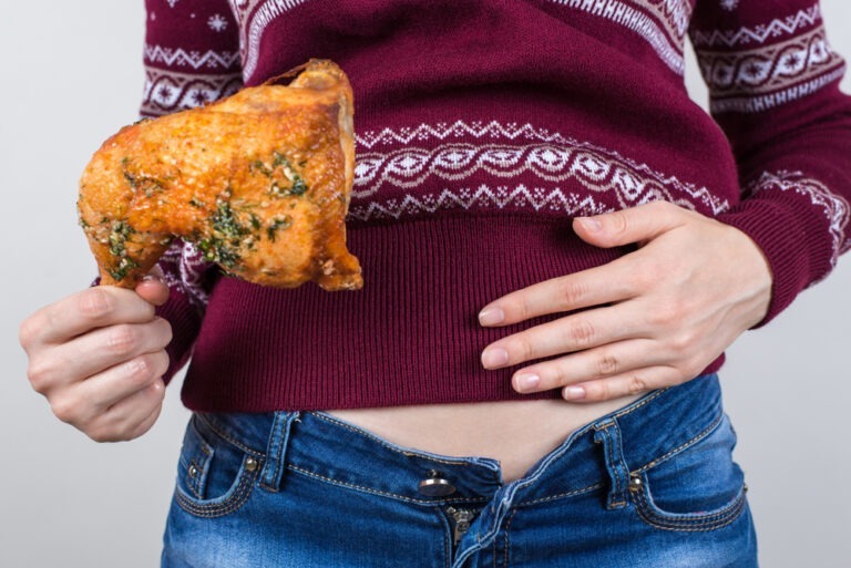 person holding stomach and a turkey leg