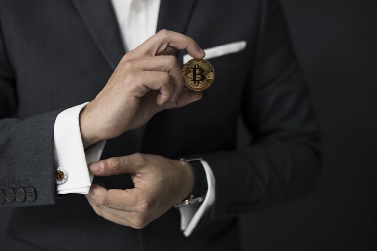 Person's hands holding a bitcoin and adjusting their cufflinks.
