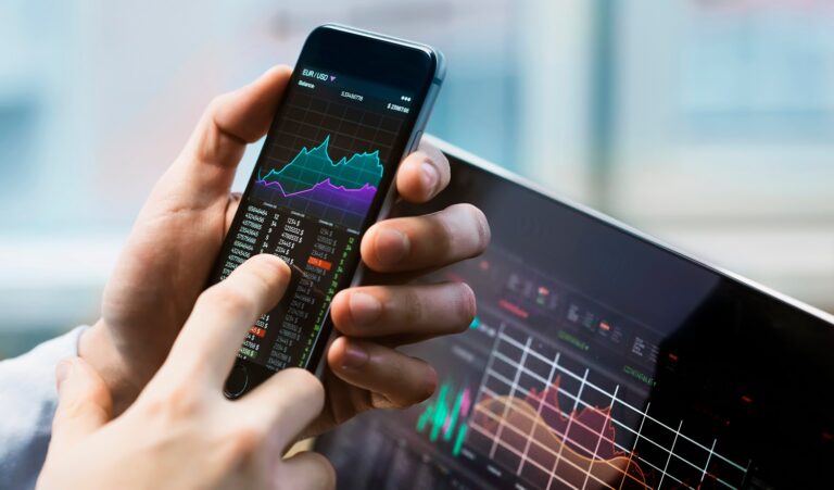 Phone and laptop with stock market graphics