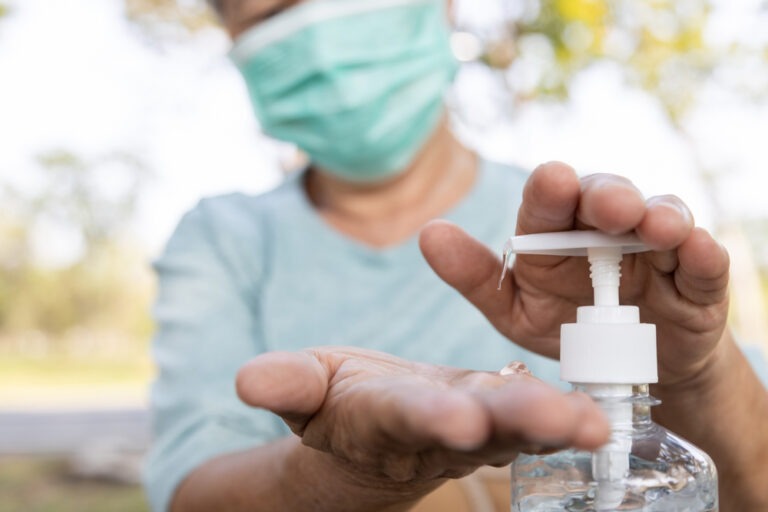 a medical worker wearing a mask and pumping hand sanitizer