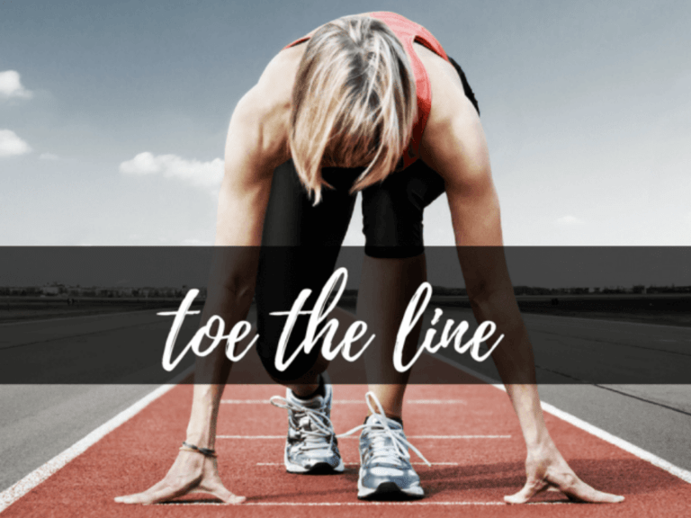 a female track racer at the starting line with the text "toe the line"