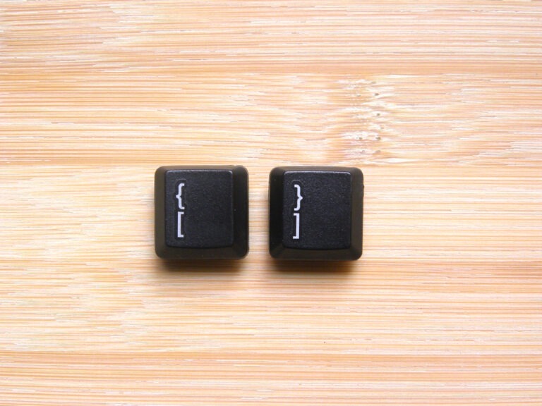 isolated bracket keys from a keyboard sitting on a wooden table.