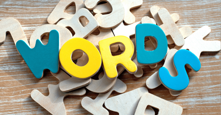 A pile of white plastic or wooden letters with the letters that spell W-O-R-D-S painted bright colors