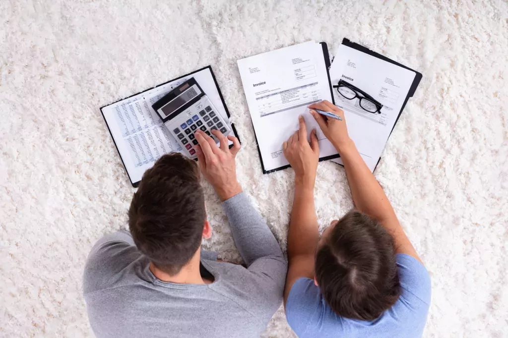 A view looking down at a couple who have papers and a calculator in front of them.