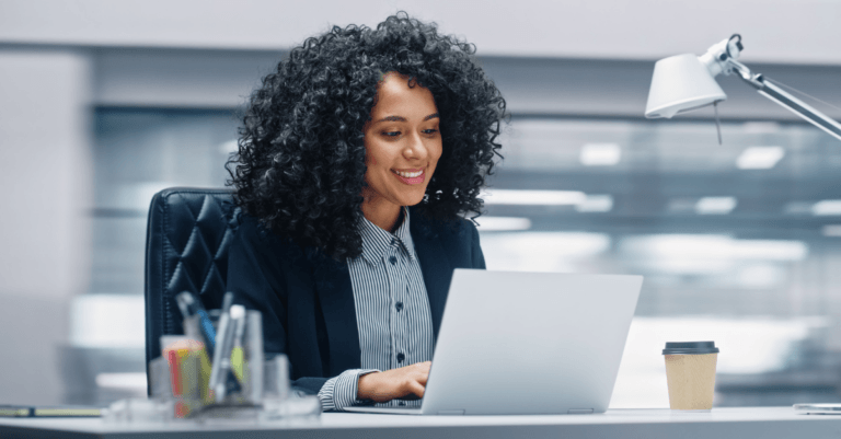 A young African American businesswoman at a laptop computer in a modern looking office