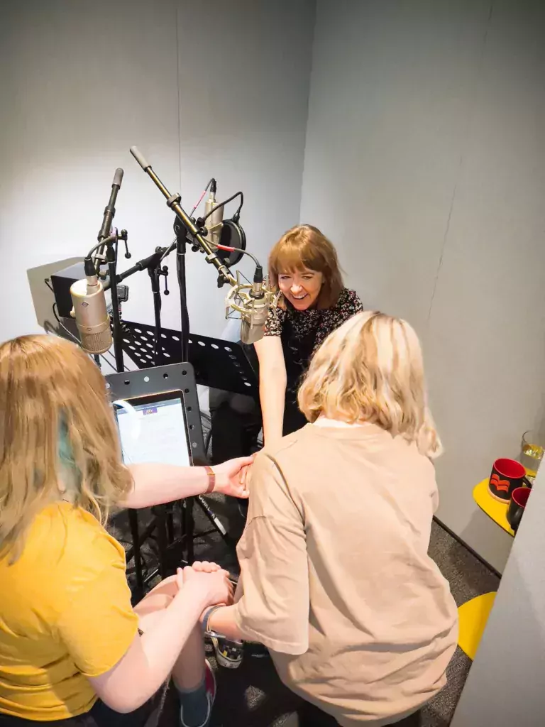 Three people in a recording studio. 