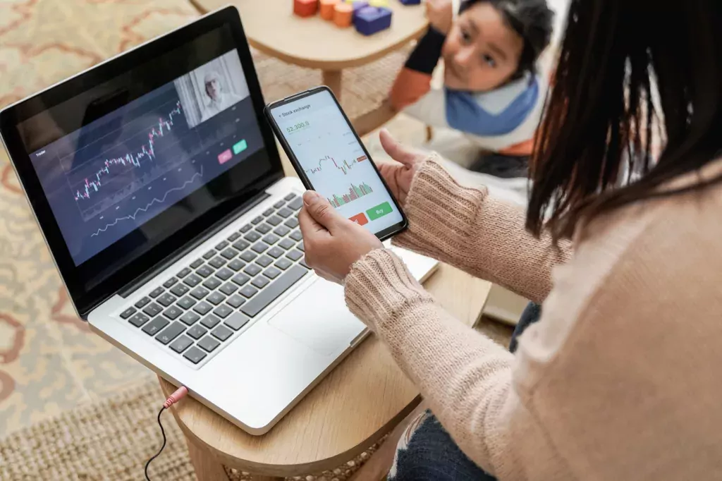 Woman trading stocks on phone and laptop