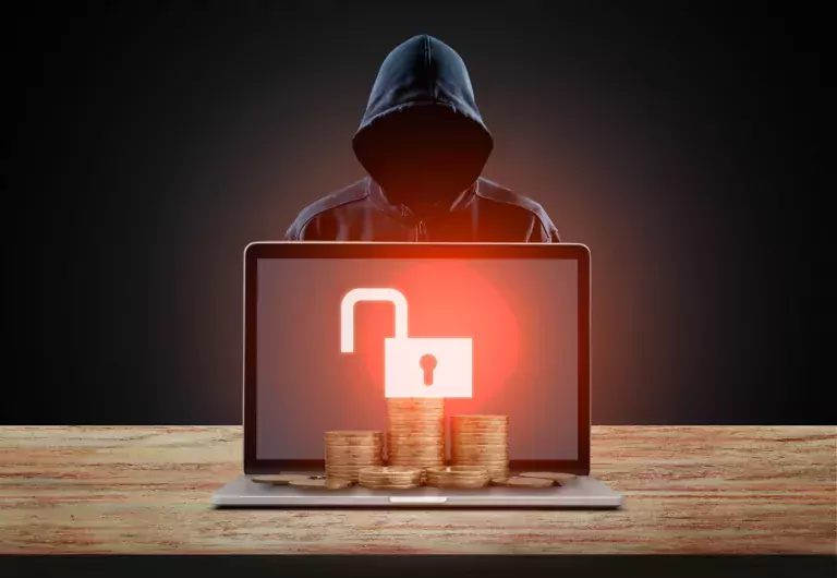 Bitcoin and cryptocurrency cybersecurity concept with hacker behind the laptop with coins.