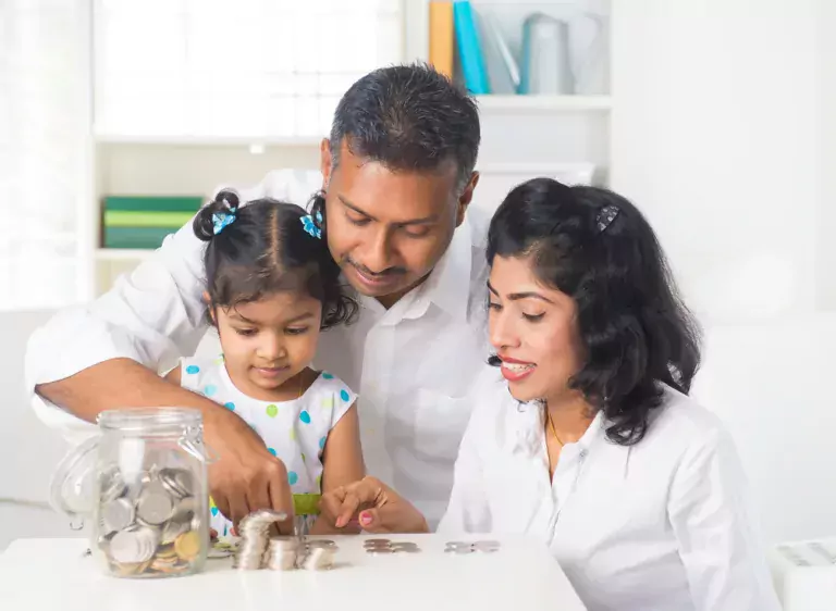 Family of three putting coins into a jar