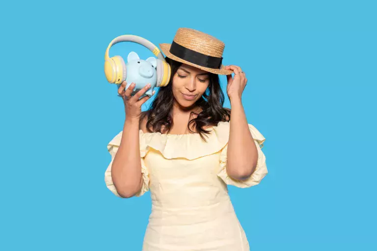 Woman with piggy bank wearing headphones pressed to her ear