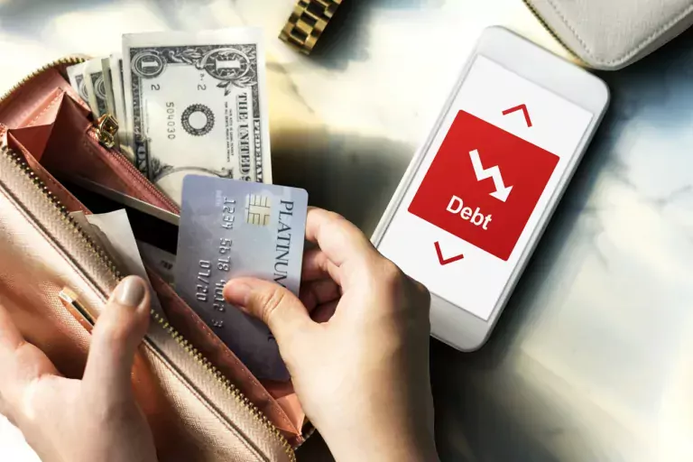 Wallet with dollars and cards, and a cell phone with the word "debt" on it