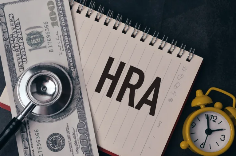 Note pad with HRA written on it and a dollar with a stethescope on it