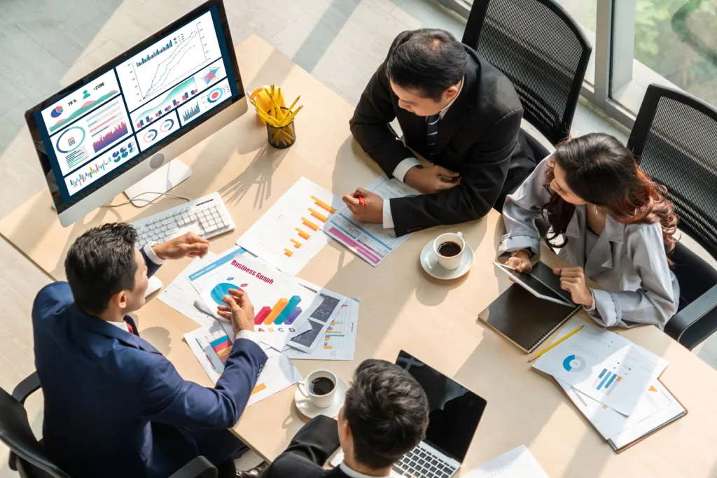 People around a table with coffee and spreadsheets