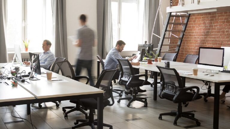 Open concept office with brick wall and tables with people working at computers