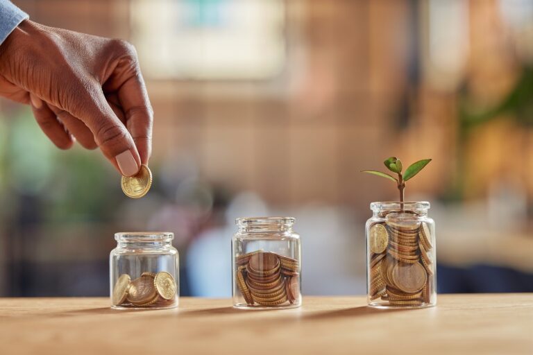 Three glass jars of coins, one with a small plant growing out of it