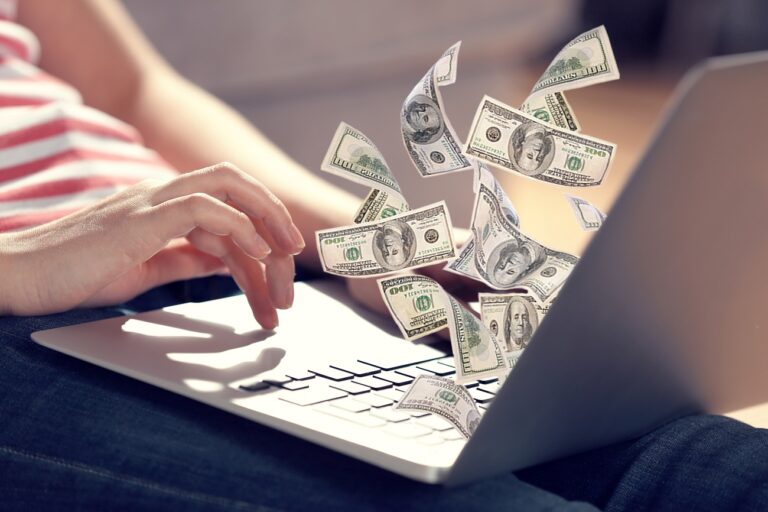 Person with laptop with dollar bills coming out of it on their lap.